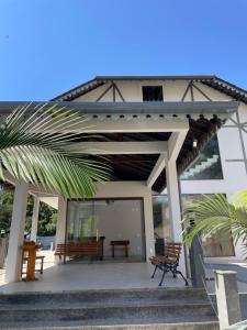 une maison avec une terrasse couverte dotée de 2 chaises et d'un banc dans l'établissement Hospedagem Estação, à Domingos Martins
