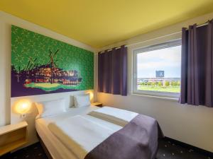 um quarto com uma cama grande e uma janela em B&B Hotel Oberhausen am Centro em Oberhausen