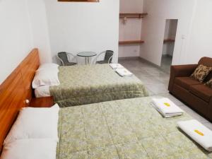 Cette chambre comprend deux lits et un canapé. dans l'établissement Excelente ubicación! Bellas y cómodas habitaciones en el centro de Oxapampa, à Oxapampa