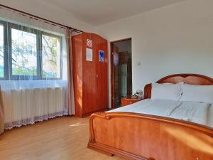 a bedroom with a wooden bed and a large window at Pensiunea Agroturistica Ica in Valea Drăganului