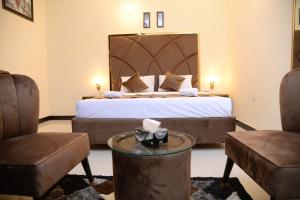 a hotel room with a bed and two chairs at Go Room Hotel Lahore in Lahore