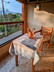 een vaas op een tafel met een stoel en een raam bij Chalés de Santana in Tiradentes