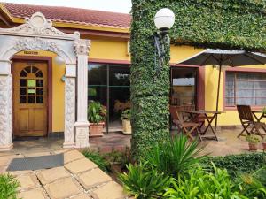 a yellow house with a table and an umbrella at Acre of Africa Guesthouse in Boksburg