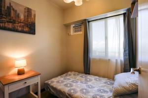 a small bedroom with a bed and a window at Verdon Parc 2 bedroom apartment Ocean View in Davao City