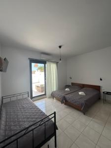 a bedroom with two beds and a large window at Zefyros Studios in Plaka