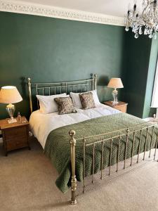 a bedroom with a large bed with a green wall at The Lodge at Salhouse in Norwich