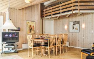 a dining room with a table and chairs and a tv at 4 Bedroom Cozy Home In Hvide Sande in Havrvig