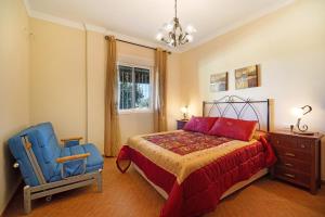 a bedroom with a bed and a blue chair at Villa Juani in Chiclana de la Frontera