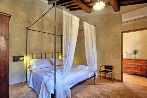 1 dormitorio con cama con dosel y silla en La Pimpinella di Semifonte, en San Donnino
