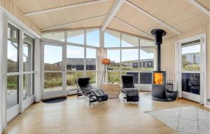 a living room with a fireplace and chairs and windows at Gorgeous Home In Hvide Sande With Sauna in Hvide Sande