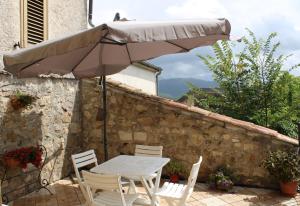 una mesa y sillas bajo una sombrilla en un patio en La collina degli ulivi, en Conocchia
