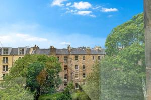 un gran edificio de ladrillo con árboles delante de él en Bright and spacious flat overlooking the Meadows en Edimburgo