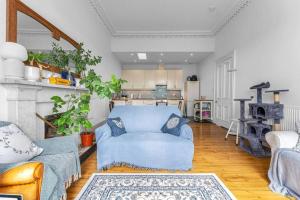 sala de estar con sofá azul y cocina en Bright and spacious flat overlooking the Meadows en Edimburgo