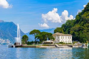 a building on the shore of a lake with a fountain at Lierna Fronte Lago in Lierna