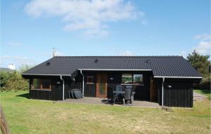 una casa negra con dos sillas delante en Beautiful Home In Hjrring With House Sea View, en Lønstrup