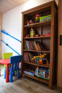 estante de libros con juguetes y silla en una habitación en Apartament Pod Świerkami, en Małe Swornigacie