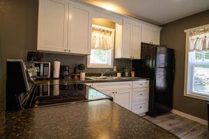 a kitchen with white cabinets and a black refrigerator at Mountain Haven Dragon's Nest Cabin in Robbinsville +19 photos