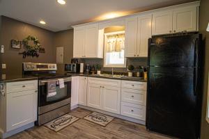 a kitchen with white cabinets and a black refrigerator at Mountain Haven Dragon's Nest Cabin in Robbinsville