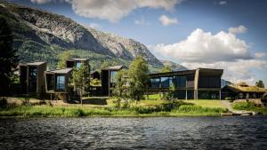 a house on a lake with mountains in the background at Elva Hotel in Skulestadmo