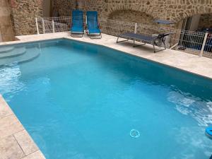 uma piscina com duas cadeiras azuis e um banco em Chez Janick & Hervé em Lemps
