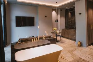 Apartamenty Kopernika 7 في جلونا غورا: حمام كبير مع حوض استحمام وتلفزيون
