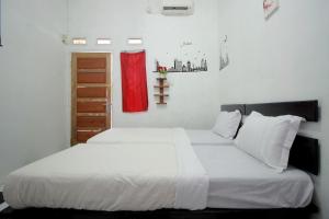 a bedroom with a bed with white sheets and a red curtain at OYO 2362 Wisma Ria in Lubuklinggau