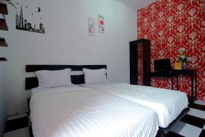 a bedroom with a white bed and a red wall at OYO 2362 Wisma Ria in Lubuklinggau