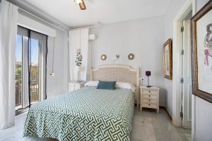 ein weißes Schlafzimmer mit einem Bett und einem großen Fenster in der Unterkunft Magnifico piso en la playa in El Puerto de Santa María