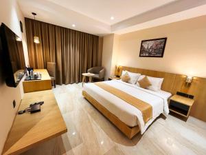 グワーハーティーにあるSachika Hotels, Guwahatiの大きなベッドとデスクが備わるホテルルームです。