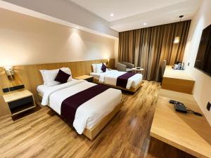 a hotel room with two beds and a television at Sachika Hotels, Guwahati in Guwahati