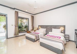 two beds in a room with two windows at Tropical Tree in Fehendhoo