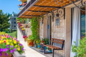 un banco sentado fuera de un edificio con flores en Apart hotel M S KATUNJANIN, en Herceg-Novi