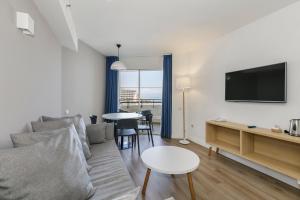 a living room with a couch and a tv and a table at Sol Puerto Marina in Torremolinos