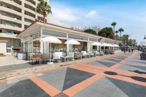 a building with tables and white umbrellas on a street at Sol Puerto Marina in Torremolinos
