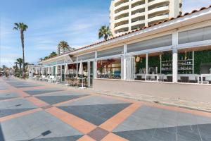 a building with tables and chairs on a street at Sol Puerto Marina in Torremolinos