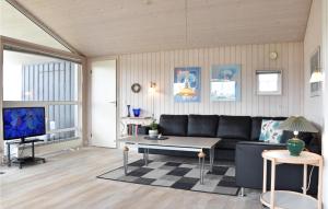 BjerregårdにあるNice Home In Hvide Sande With Saunaのリビングルーム(黒いソファ、テレビ付)