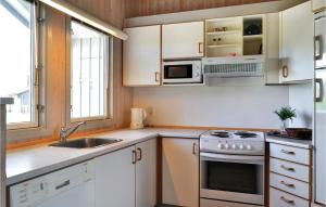uma cozinha com armários brancos, um lavatório e um fogão em Nice Home In Hvide Sande With Wifi em Bjerregård