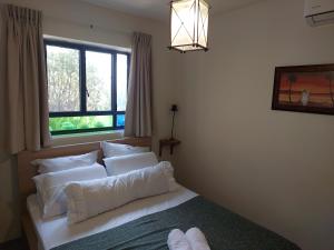 Un dormitorio con una cama con almohadas blancas y una ventana en Neve Nof en Rosh Pinna