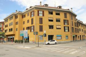 um edifício amarelo com um carro branco estacionado em frente em Lovely Apartment near Canal - Via Foscolo em Corsico