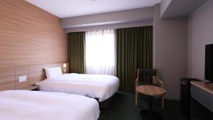 a hotel room with two beds and a television at Dormy Inn Aomori Natural Hot Spring in Aomori