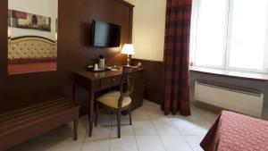 Habitación de hotel con escritorio, TV y cama en Domus Augusta, en Roma