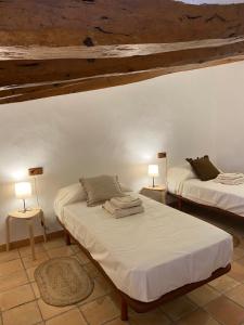 1 dormitorio con 2 camas y 2 lámparas en las mesas en Masia Ca la Jepa, en Juncosa