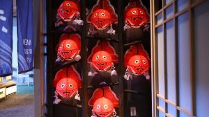 a rack of red helmets with faces on them at Dormy Inn Aomori Natural Hot Spring in Aomori