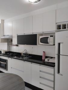 a white kitchen with white cabinets and a microwave at Alcimar Zuzo in Mogi das Cruzes