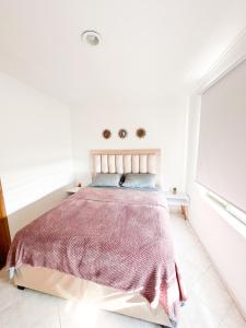 ein weißes Schlafzimmer mit einem Bett mit einer rosa Decke in der Unterkunft Lujoso apartamento frente a la playa in Cartagena de Indias