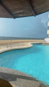 einen Pool neben einem Strand mit einem Leuchtturm in der Unterkunft Lujoso apartamento frente a la playa in Cartagena de Indias