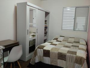 um quarto com uma cama, uma secretária e uma janela em Alcimar Zuzo em Mogi das Cruzes