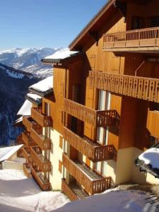 un edificio con balcones de madera en la nieve en Paradiski proche des pistes plan peisey, en Peisey-Nancroix