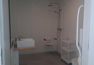 een witte badkamer met een wastafel en een douche bij La Compagnie des Moëres in Veurne