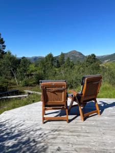 2 chaises assises au-dessus d'une terrasse dans l'établissement Solsetra - Mountain Majesty Family Log Cabin, à Hovden